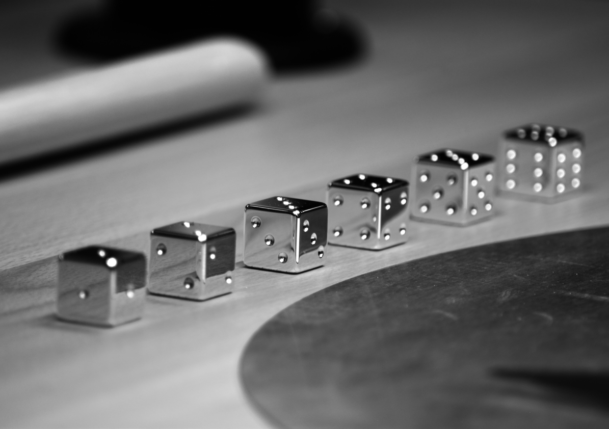 Six sculptural dice in a row, each showing a single number on every face